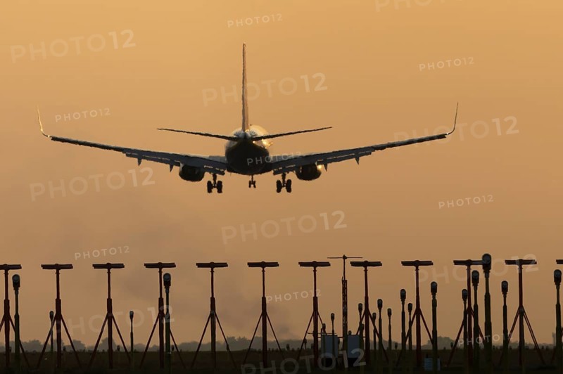Boeing 737 jet passenger aircraft of Ryanair airlines landing over runway lights at sunset, London Stansted airport, Essex, England, United Kingdom