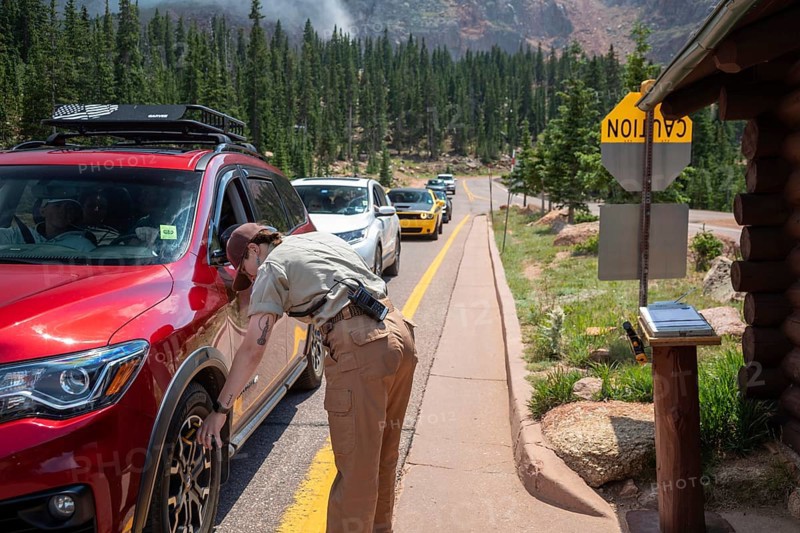 Colorado Springs, Colorado - A Pikes Peak ranger checks the temperature of brakes on a car descending 14, 115' Pikes Peak. If the brakes have become hotter than 300 degrees F, travelers must stop to let the brakes cool before continuing their descent