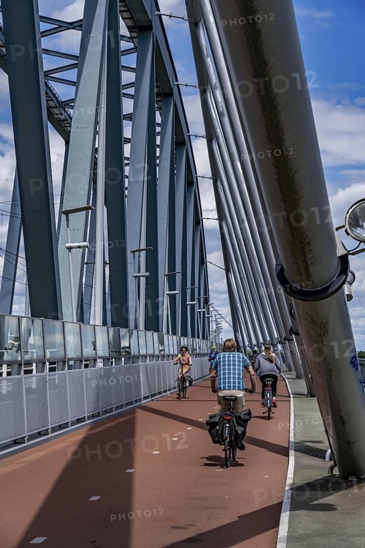 Cycle and pedestrian bridge Snelbinder Brug, over the river Waal near Nijmegen, was added to the existing railway bridge, fast cycle path connection from the city centre of Nijmegen and the new housing estates in the Waalsprong district, Netherlands