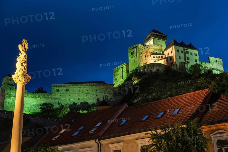 Night shot of the plague column column commemorating the victims of the plague at the beginning of the 18th century, in the background is Trencín Castle, Capital of Culture 2026, Trencín, Slovakia