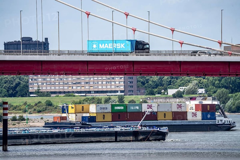 Barges on the Rhine at Ruhrort harbour, container freighter on uphill journey, Friedrich-Ebert-Bridge, road bridge over the Rhine between Homberg and Ruhrort, Maersk container on lorry on the bridge, Duisburg, North Rhine-Westphalia, Germany
