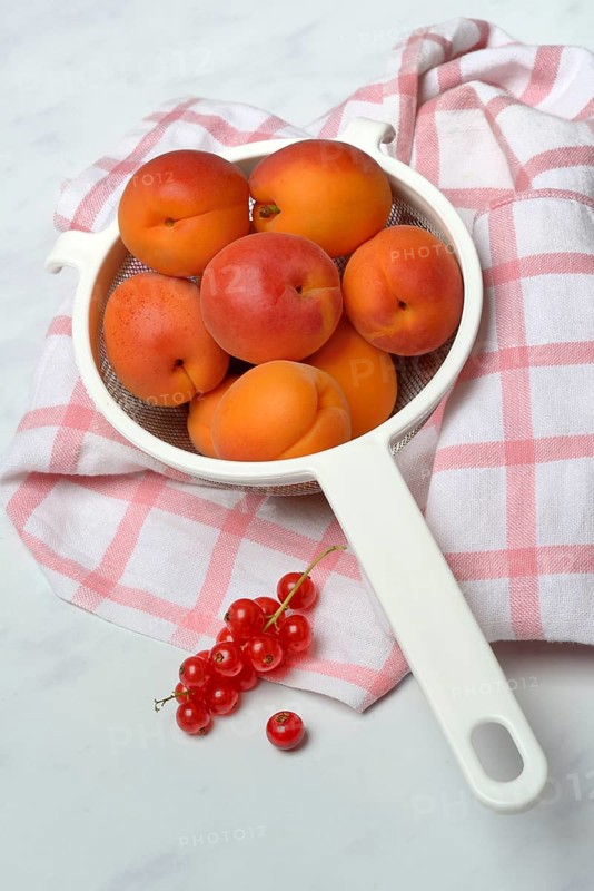 Apricots in a colander and redcurrants