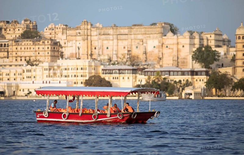 Excursion boat on Lake Pichola, behind the City Palace in the evening light, Udaipur, Rajasthan, India