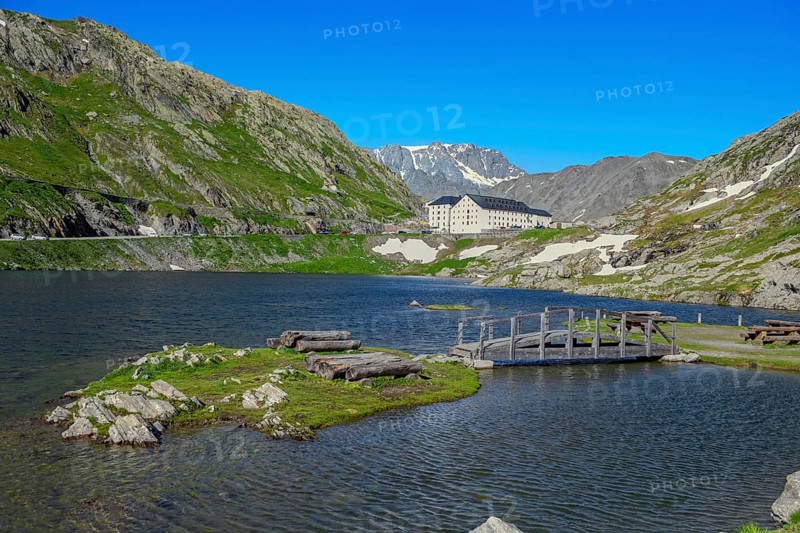View from Italian side on small island in Lac du Grand Saint Bernard in the background on Swiss territory historic Auberge Herberge Hospice on pass summit of 2473 metres high alpine pass Great Saint Bernard, Saint-Rhémy-en-Bosses, region Valle d'Aosta, Italy