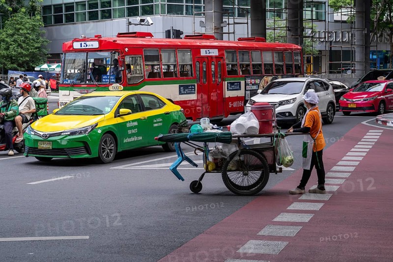 Street crossing woman with cookshop, Bangkok, Thailand