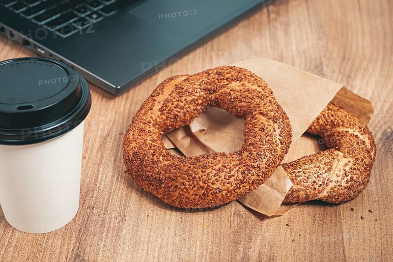 Simits with coffee on a wooden table, with a laptop, in a cozy working environment, snack, breakfast, no people