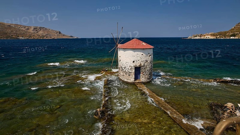 Historic windmill stands in the turquoise sea, surrounded by waves and a clear sky, Agia Marina, Leros, Dodecanese, Greek Islands, Greece