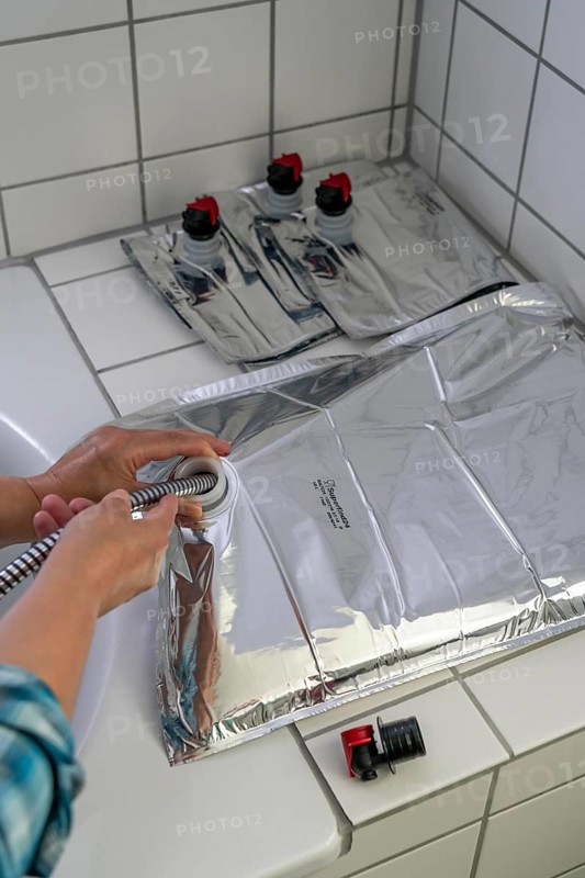 Filling a 10 litre water bag, for storing drinking water at home, as an emergency reserve in the event of a blackout or similar, lightweight, foldable, reusable bag made of multi-layer film, with dispensing device, for long-term storage of up to one year, recommended 3 litres of drinking water per person, for 10 days of storage