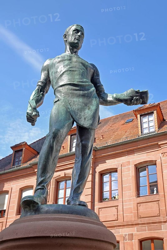 Cobbler's fountain with cobbler Johann Joß sculpture as a symbol of the former shoe industry and shoe production, manufacture, shoes, hammer, craftsman, male figure, view from below, presentation, show, bronze sculpture, fountain, Pirmasens, Rhineland-Palatinate, Germany