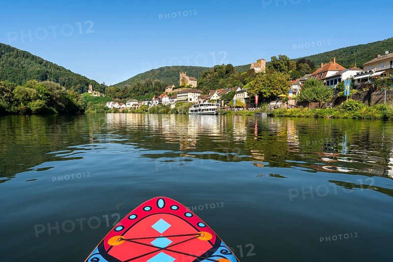SUP board on the Neckar near Neckarsteinach. The ruins of Hinterburg Castle on the top left, Mittelburg Castle in the centre and Vorderburg Castle on the right. An excursion steamer on the quay. Neckarsteinach, Odenwald, Rhine-Neckar district, Baden-Württemberg, Germany