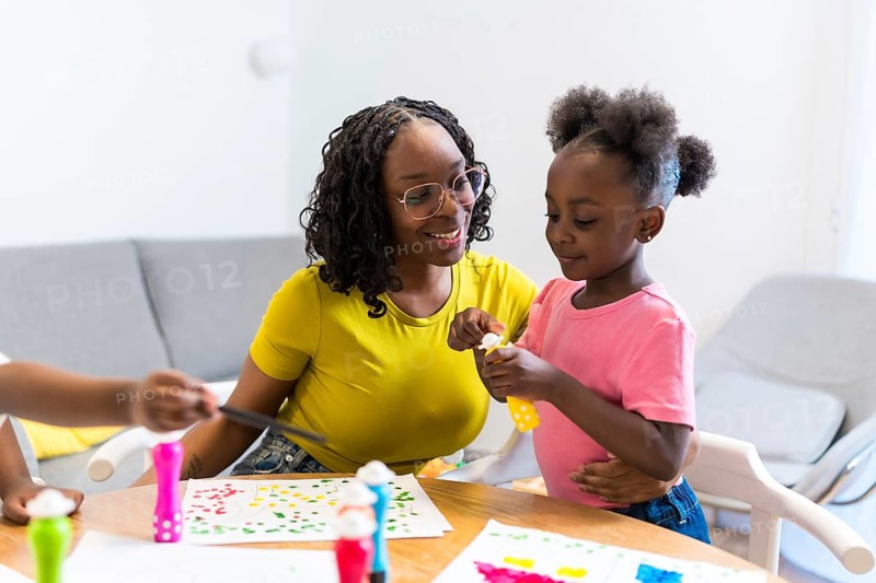 Mother and daughter bonding over a painting project, demonstrating love, care, and creativity in a warm home setting