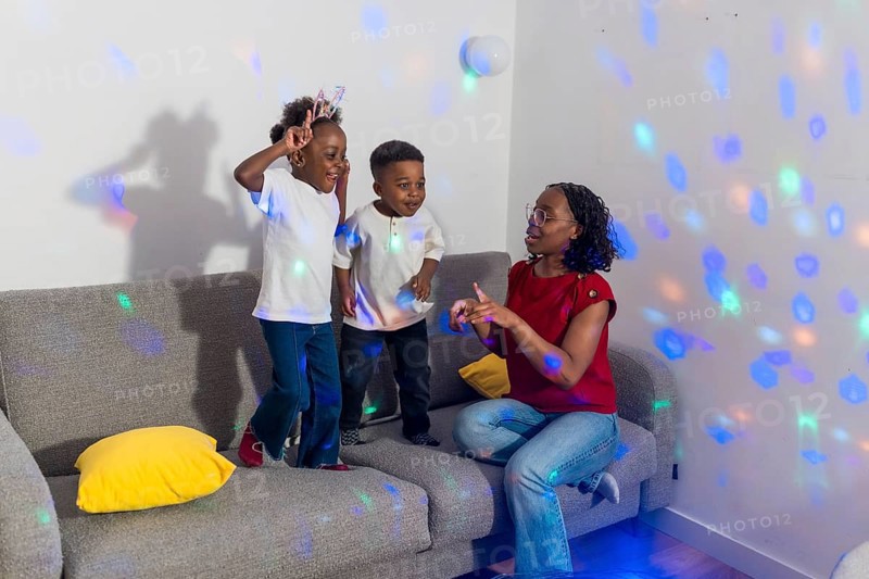 Mother and her two children enjoying dancing together in the living room, illuminated by colorful disco ball lights