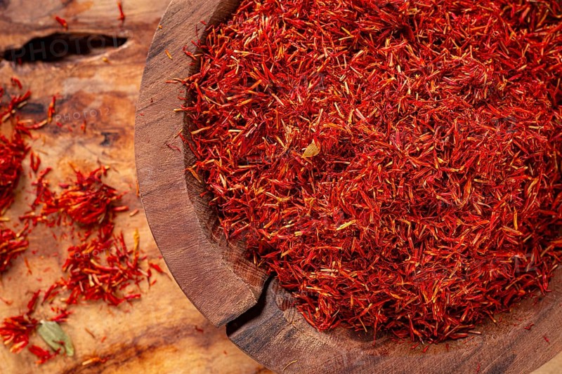 Spice saffron threads, in a wooden bowl, on a wooden table, top view, close-up
