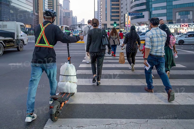 Man crossing a pedestrian crossing on an electric scooter, Abu Dhabi, United Arab Emirates