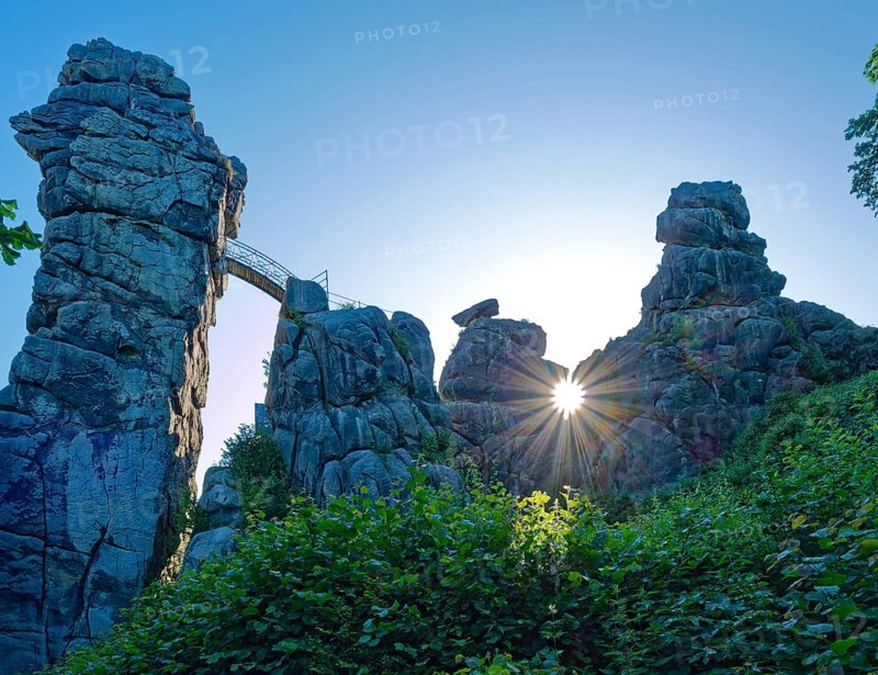 The morning sun shines through an opening in the Externsteine. The Externsteine, a sandstone rock formation around 40 metres high in the Teutoburg Forest, are a natural sight and are a protected natural and cultural monument. They are regarded as a place of power and are considered to have special cultural and historical significance. Horn-Meinberg, North Rhine-Westphalia, Germany