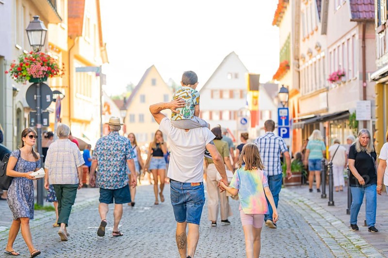 Families and pedestrians stroll through a lively old town street in sunny weather, 950 years of Weil der Stadt celebrations, Böblingen district, Germany