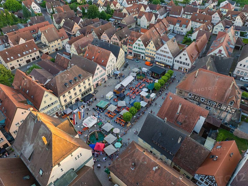 Lively town festival with numerous visitors and green trees surrounded by buildings seen from the air, 950 years of Weil der Stadt celebration, Böblingen district, Germany