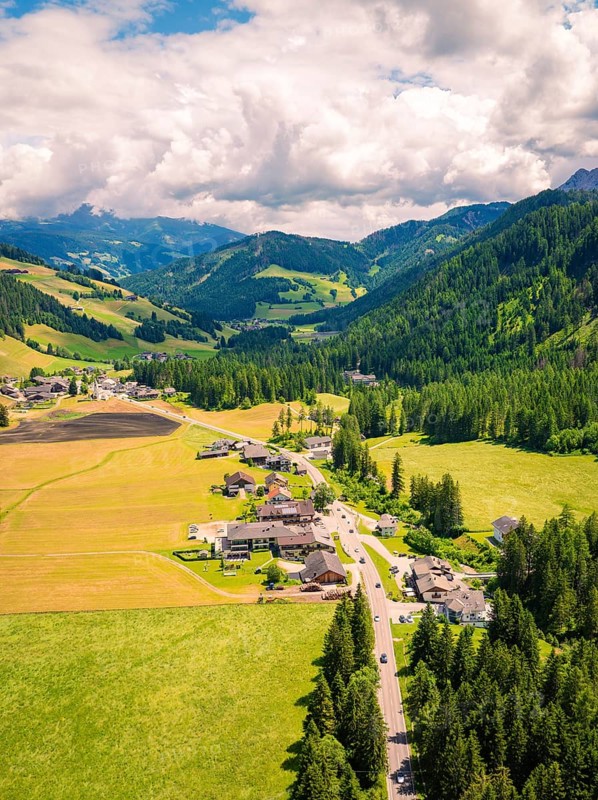 Aerial view of an idyllic valley with green meadows, forests and a small village