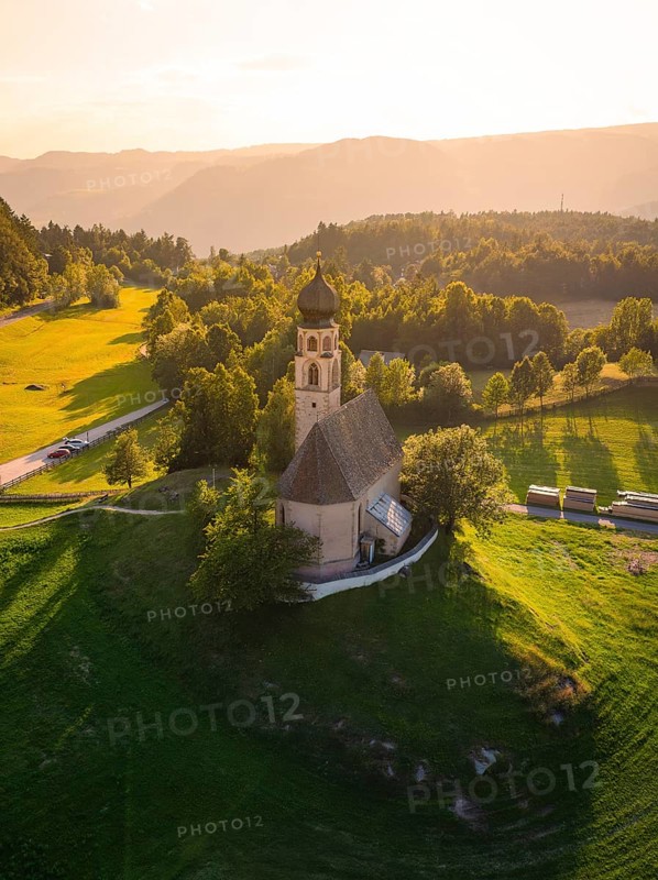 Idyllic church on a hill surrounded by green countryside and warm sunset light