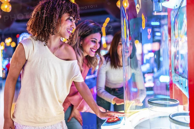 Three friends enjoying their time together playing an arcade game in a colorful entertainment venue