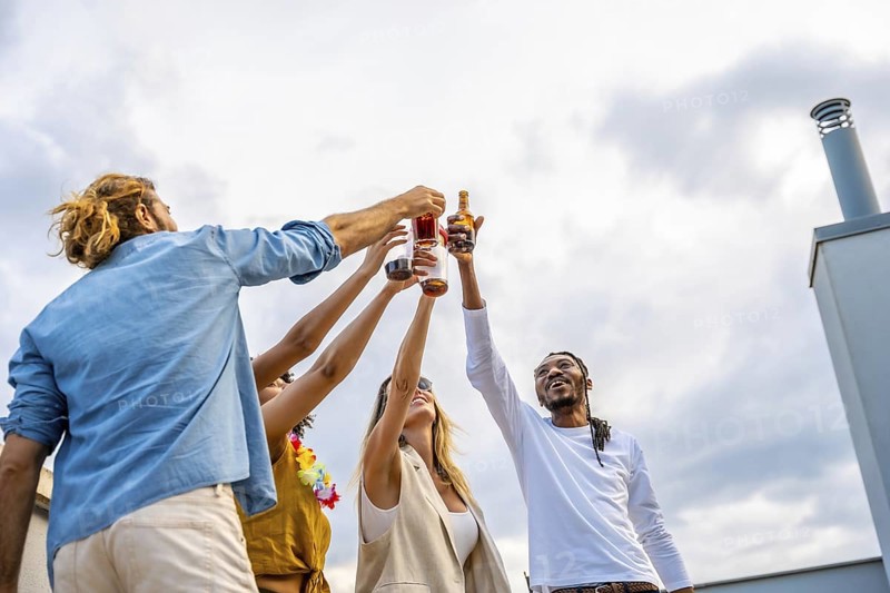 Happy multi ethnic friends raising their glasses for a celebratory toast, enjoying a rooftop party