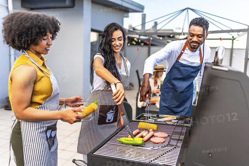 Chefs grilling delicious barbecue food for a rooftop party, preparing vibrant vegetables and savory meats under the warm sun