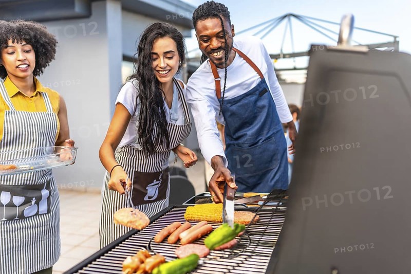 Happy friends enjoying a rooftop barbecue party, grilling delicious food, sipping drinks, and celebrating together under the evening sun