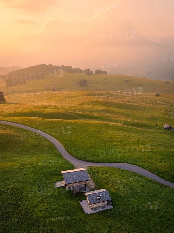 Houses and streets in a hilly landscape in warm evening light, Alpe di Siusi, Dolomites, South Tyrol, Italy