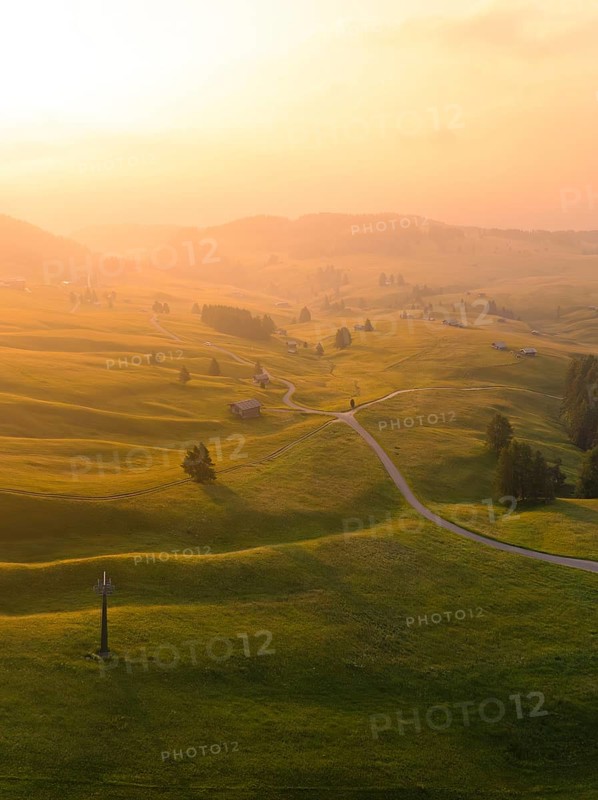 Hilly landscape at sunset with winding paths and warm light, Alpe di Siusi, Dolomites, South Tyrol, Italy