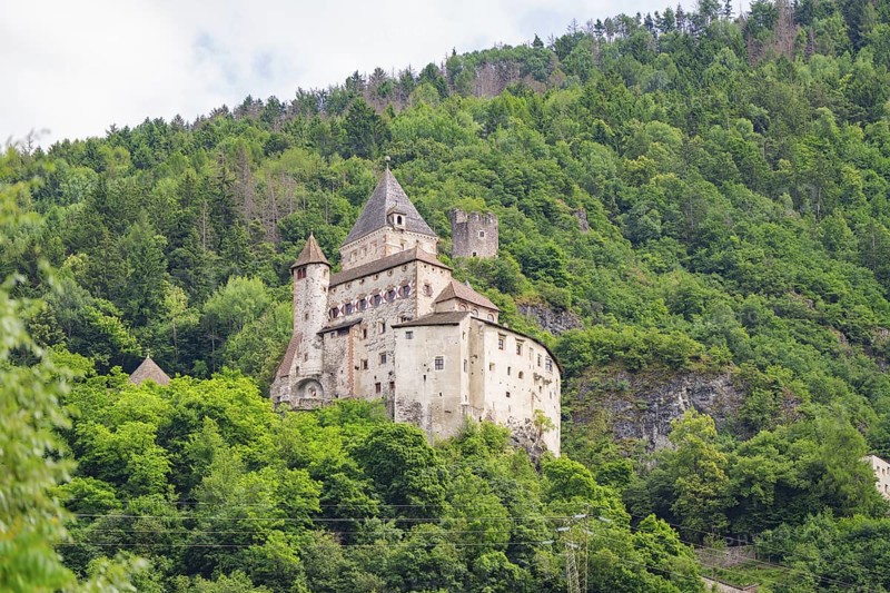 Historic castle complex on a wooded hill with defence towers and walls, Dolomites, South Tyrol, Italy