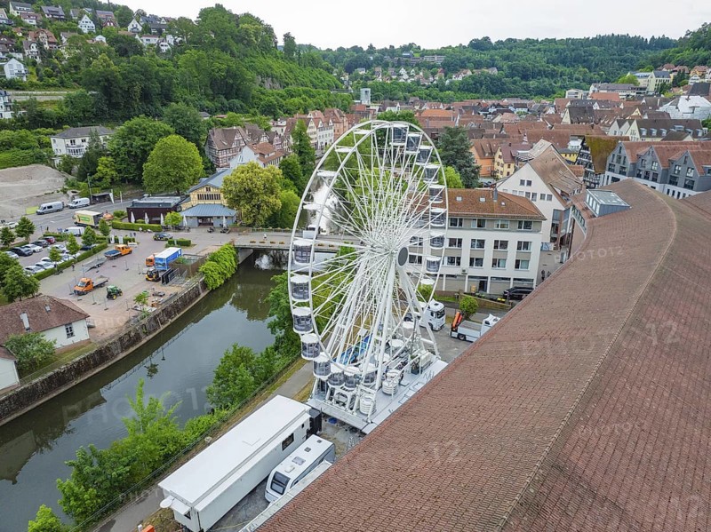 Aerial view of a Ferris wheel in the middle of a town in summer weather and wooded surroundings, construction of a Ferris wheel, Calw, Black Forest, Germany