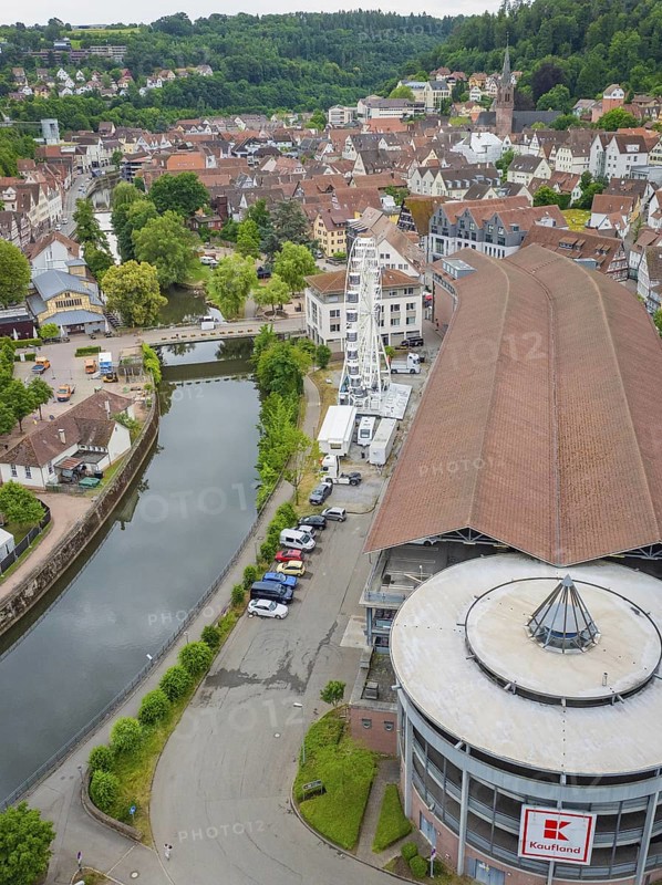 Large building with Ferris wheel by the river in a green hilly village, Ferris wheel construction, Calw, Black Forest, Germany