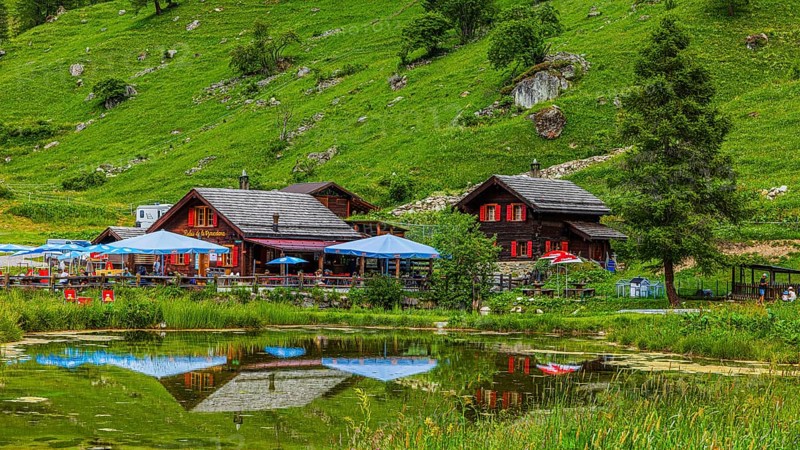 Huts and parasols reflected in the pond, Relais Tzoucdana, Zinal, Val d'Anniviers, Valais Alps, Canton Valais, Switzerland