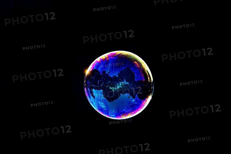 A shimmering and floating soap bubble in the colours of the rainbow against a black background, Recklinghausen, Germany