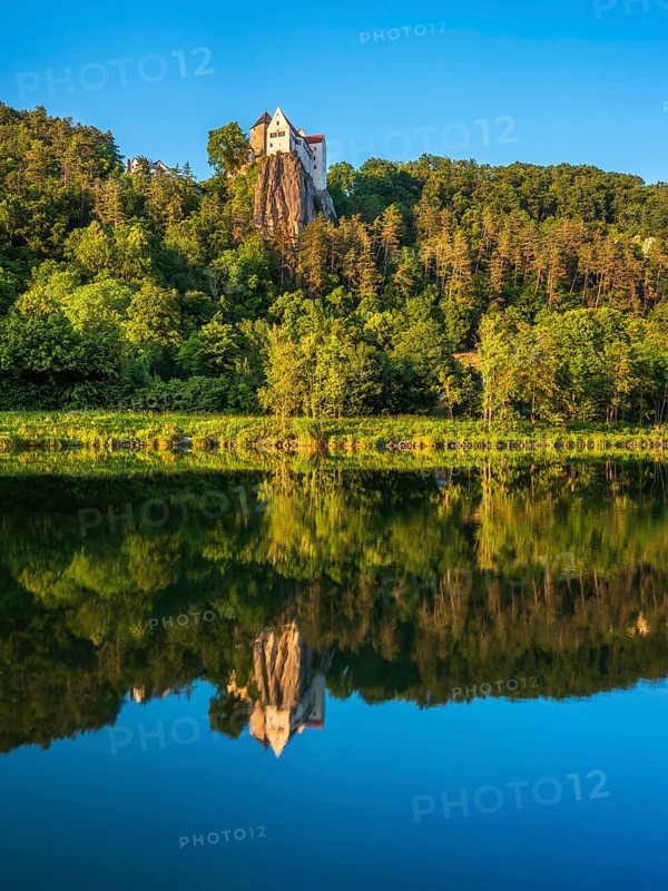 Prunn Castle on a steep cliff above the Altmühl Valley in the evening light, reflection in the river Altmühl as part of the Main-Danube Canal, near Riedenburg, Altmühl Valley nature park Park, Lower Bavaria, Germany