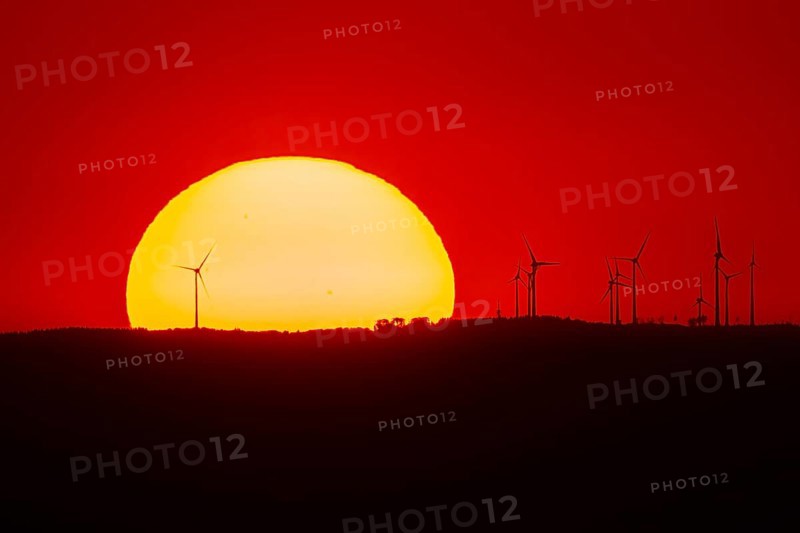 From the summit plateau of the Großer Feldberg in the Taunus mountains, you can watch the sun set behind several wind turbines on the distant horizon, Hesse, Germany