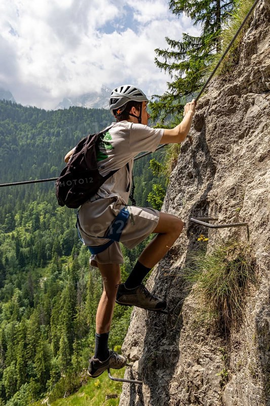 Mountaineer climbing over a steep ladder in the Isidor via ferrata, Grünstein, Schönau am Königssee, Berchtesgadener Land, Upper Bavaria, Bavaria, Germany