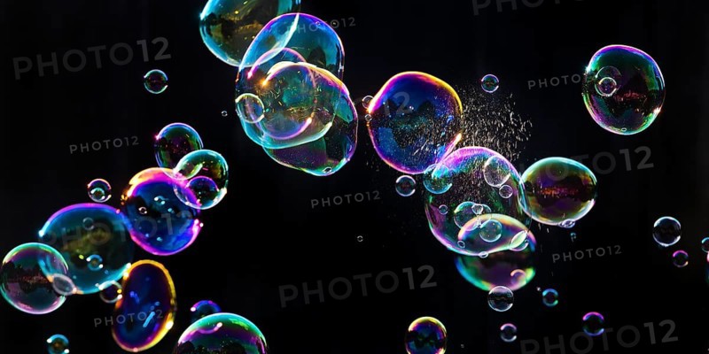 Iridescent soap bubbles with a just burst bubble in front of a black background, Recklinghausen, North Rhine-Westphalia, Germany