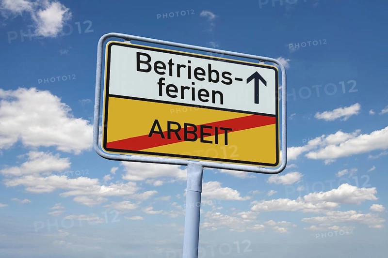 (photomontage) : Town exit sign with the inscription BETRIEBSFERIEN / ARBEIT against a blue sky