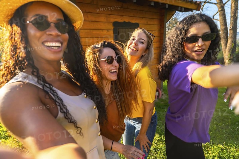 Four multi ethnic female friends are laughing and taking a selfie on a sunny day, enjoying their time together