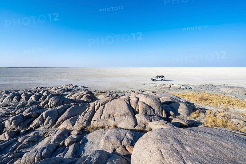 Round rocks of Kubu Island with view over the salt pan, off-road vehicle on the salt pan, Kubu Island (Lekubu), Sowa Pan, Makgadikgadi Salt Pans, Botswana