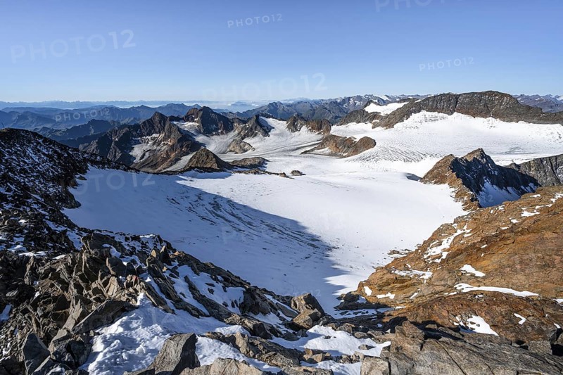 Narrow rocky ridge at the Wilder Freiger summit, picturesque high mountain landscape with snow, view of Übeltalferner glacier and rocky mountain peaks Königshofspitz and Sonklarspitze, Stubai Alps, South Tyrol, Italy