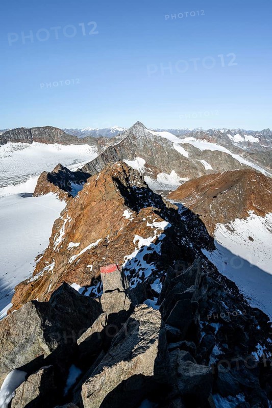 Narrow rocky ridge on the Wilder Freiger summit, picturesque high mountain landscape with snow, view of Übeltalferner glacier and rocky Wilder Pfaff mountain summit, Stubai Alps, South Tyrol, Italy