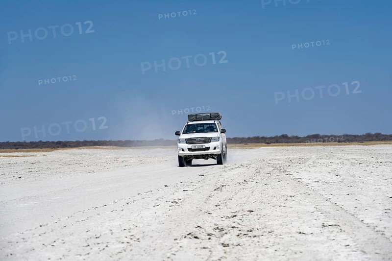 Off-road vehicle driving on a wide empty salt pan, Makgadikgadi Salt Pans, Botswana