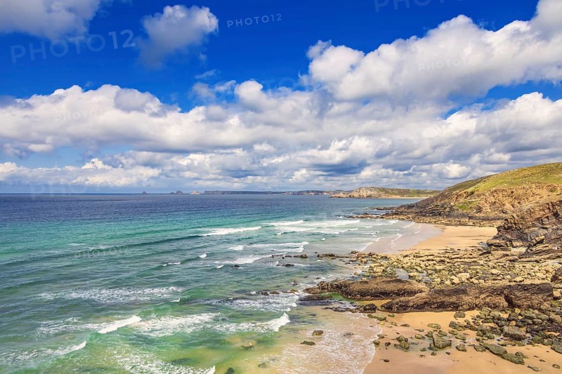 Rocky coastline with breaking waves on the shore and a scenics view to the horizon a sunny summer day with a blue sky and white clouds, Crozon Peninsula, Bretagne, France
