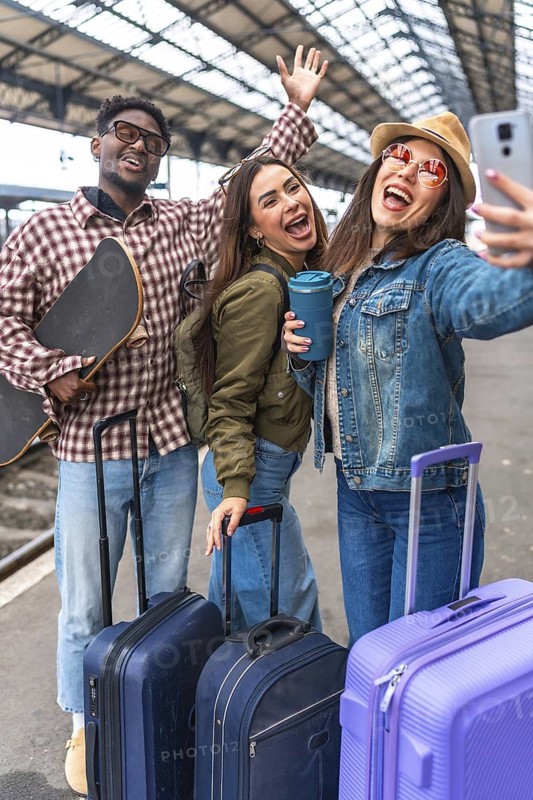 Group of cheerful young tourists taking selfie at train station, ready for their exciting adventure