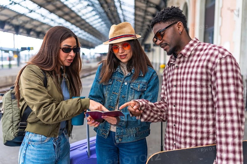 Group of young tourists checking passport and train ticket on platform, ready to travel by train