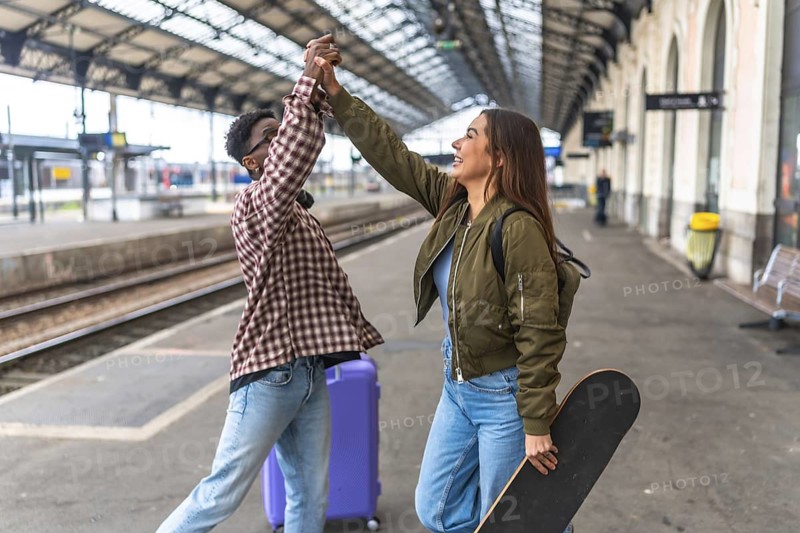 Two young tourists are giving a high five at the train station, excited for their next adventure