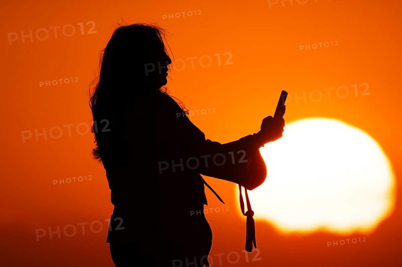 People photographing the sun setting on the horizon with their smartphones from the summit of the Großer Feldberg in the Taunus, Großer Feldberg in the Taunus, Schmitten, Hesse, Germany