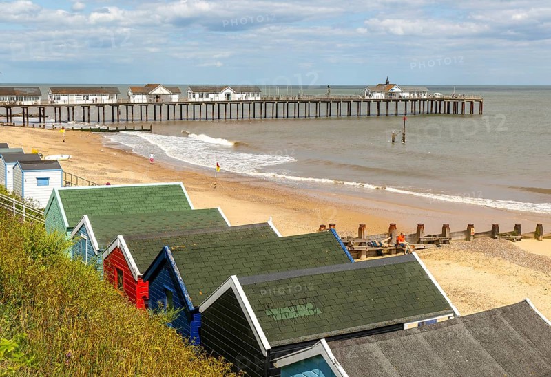 View over beach huts to sandy beach and pier, Southwold, Suffolk, England, UK